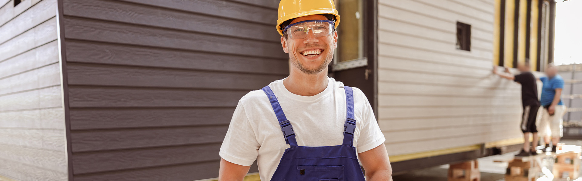 Smiling builder in front of house