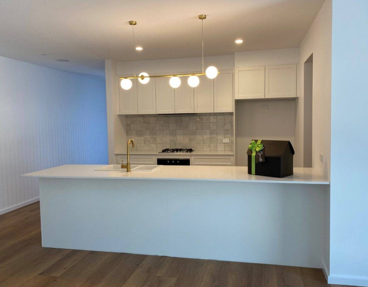 Kitchen with tiled stove backsplash, wooden panel floors and marble countertop.
