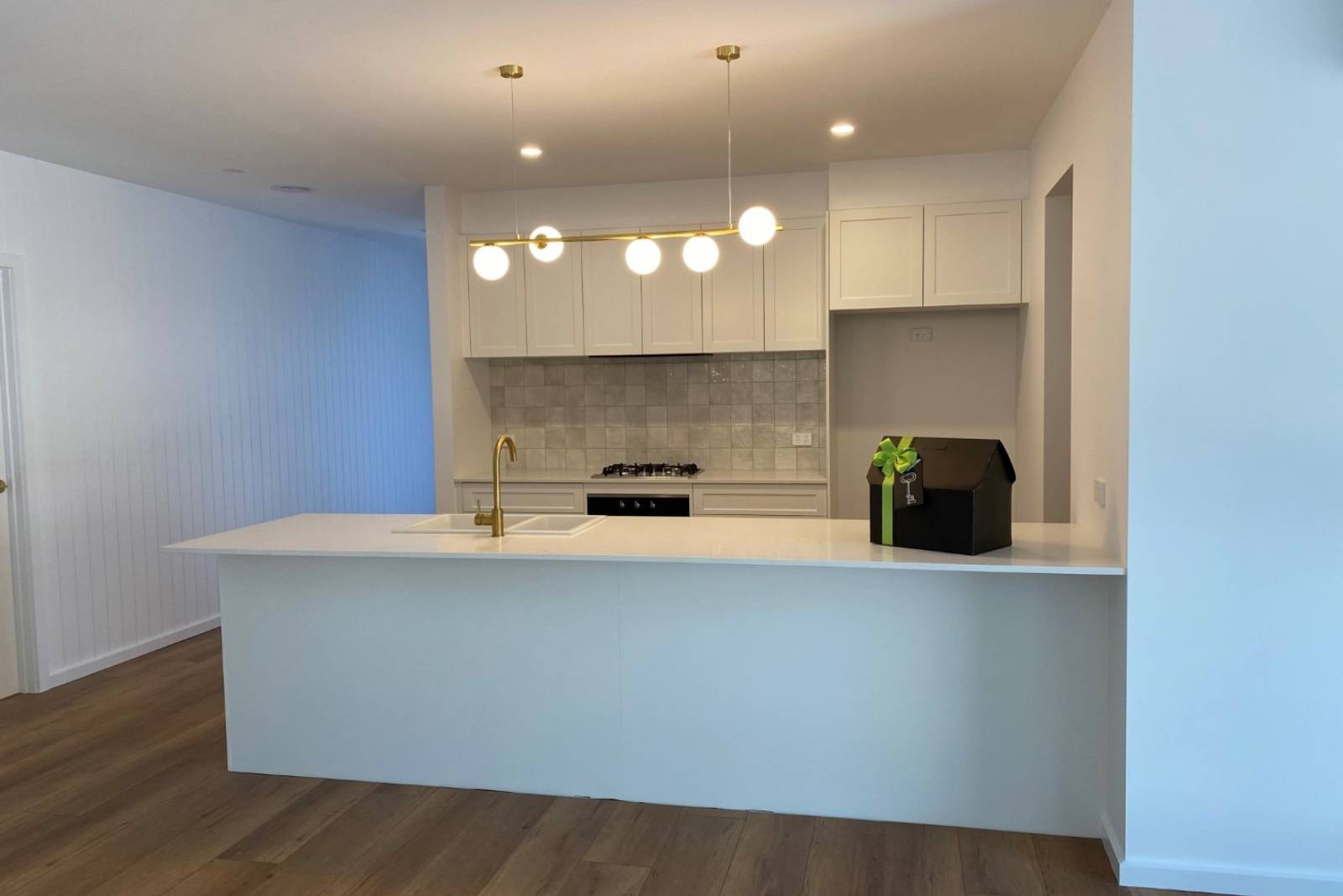 Kitchen with tiled stove backsplash, wooden panel floors and marble countertop.