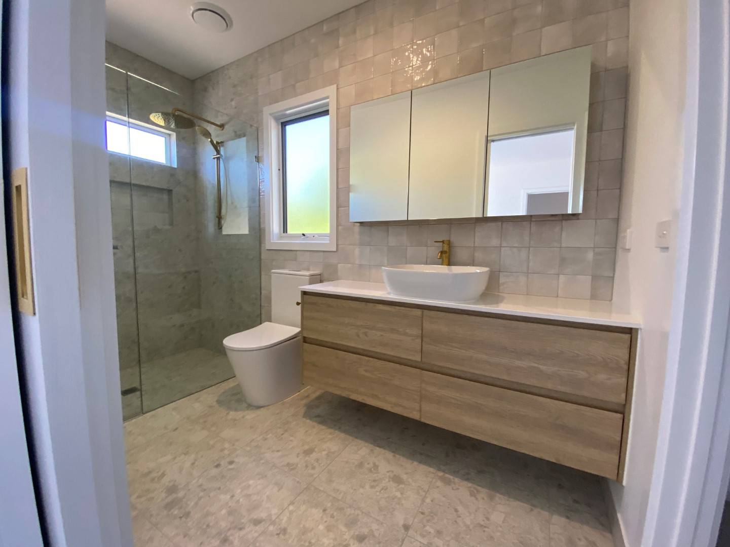 Modern bathroom with shower, toilet, floating shelves and sink